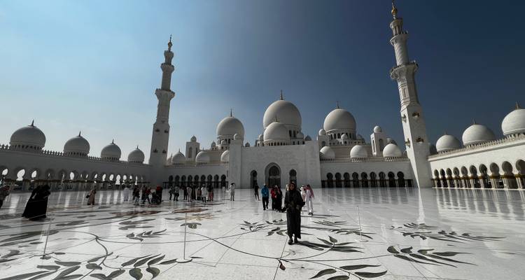 Gran mezquita con múltiples cúpulas y minaretes, personas caminando alrededor.