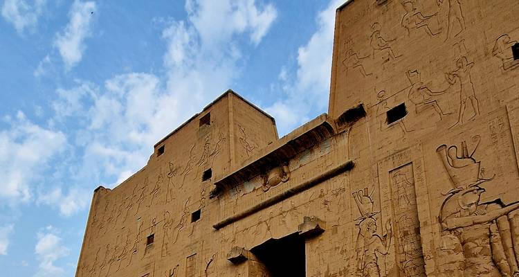 Ancient Egyptian temple with hieroglyphs against a blue sky.