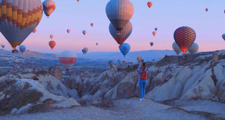Globos aerostáticos flotando sobre un paisaje rocoso durante el amanecer.