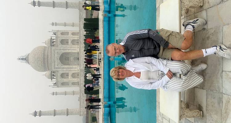 Zwei Menschen sitzen vor dem Taj Mahal.