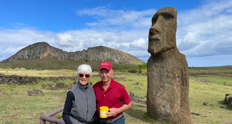 Two people posing next to a Moai statue.