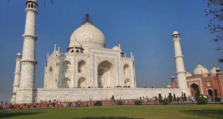 Das ikonische Taj Mahal unter einem klaren blauen Himmel mit Besuchern im Garten.