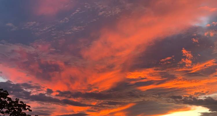 Atardecer vibrante con nubes dramáticas y tonos naranjas.