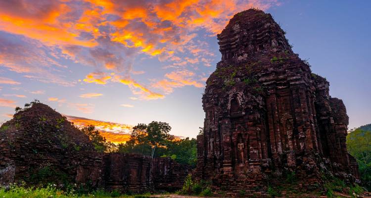 Ruines d'un temple antique avec des couleurs vives de coucher de soleil dans le ciel.