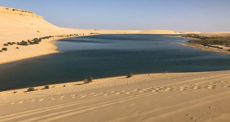 Sandige Wüstenlandschaft mit Gewässer.