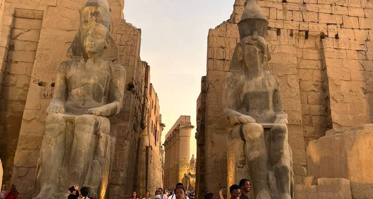 Beelden en ingang van een oude tempel met toeristen.