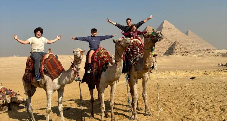 Familia montando camellos frente a las pirámides.