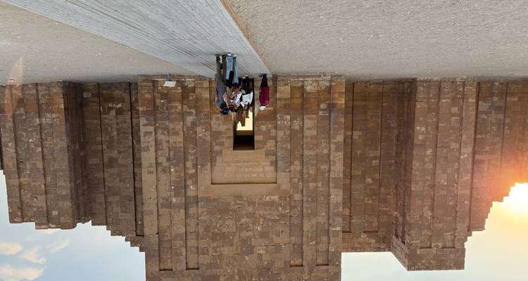 Visitantes entrando a un antiguo edificio de piedra bajo la puesta del sol.