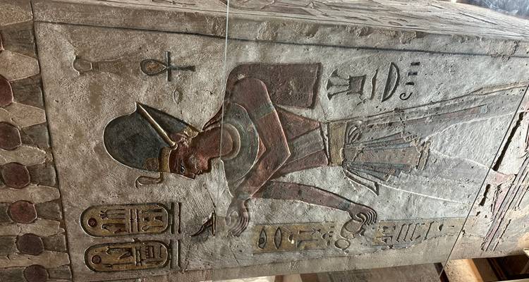 Gesneden Egyptische figuur met hiërogliefen op een muur.