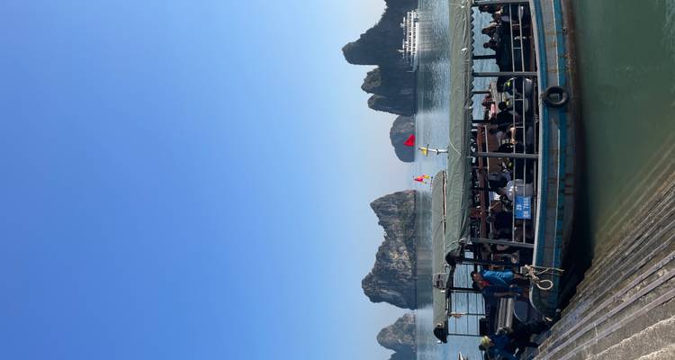 Rondvaartboot met toeristen die uitkijken naar karstformaties.