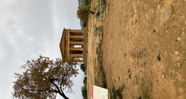 Geïsoleerde tempelstructuur met zuilen op een heuveltop.