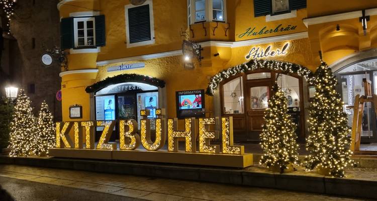 Kitzbühel bord met decoratieve verlichting op een gebouwgevel.
