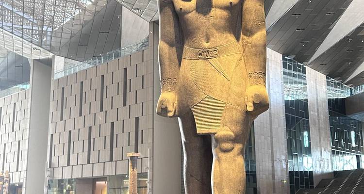 Grande statue égyptienne antique exposée à l'intérieur d'un bâtiment moderne.