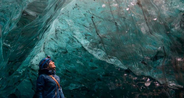 Persoon die omhoog kijkt naar het ijsblauwe plafond van een grot.