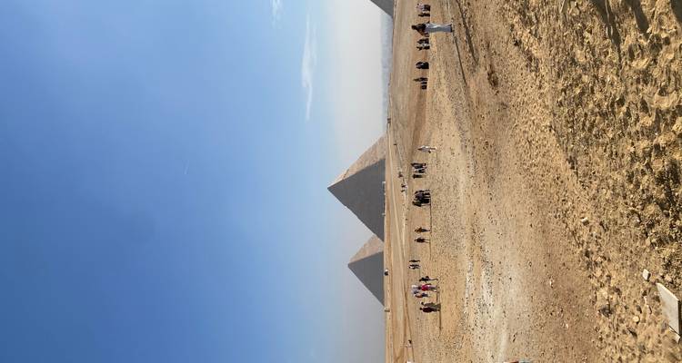 Piramides van Giza met toeristen en kamelen op de voorgrond.