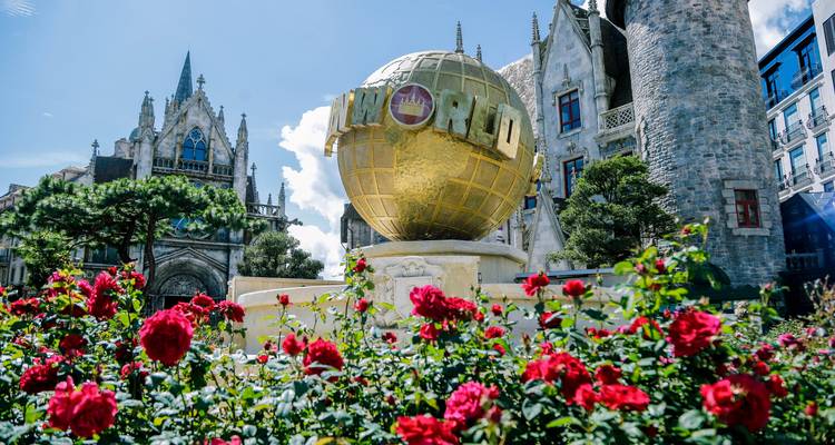 Parque temático con una gran escultura de globo terráqueo y flores.