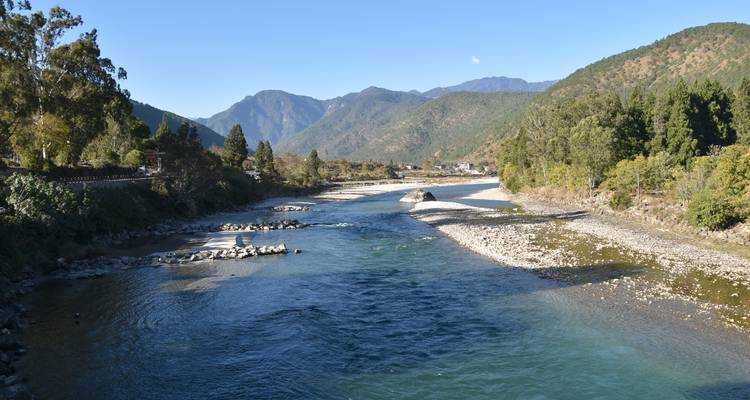 Fluss, der in einem von Bäumen umgebenen Tal fließt.