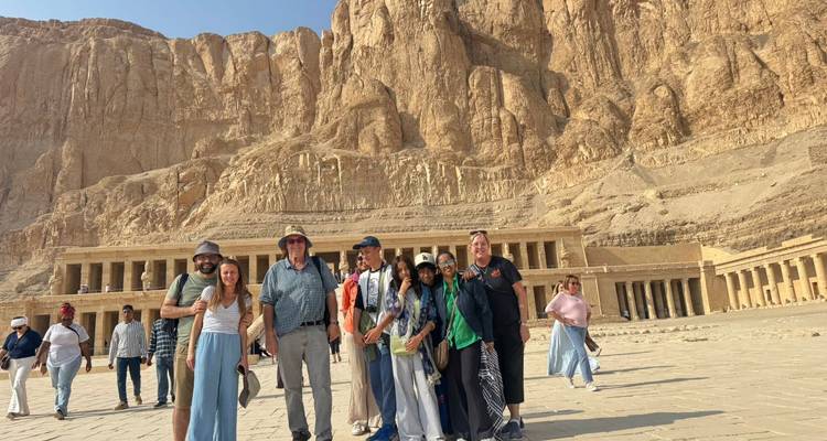 Groupe de touristes debout devant un grand temple de pierre antique.