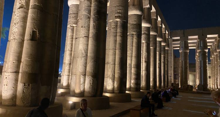 Colonnes bien éclairées d'un temple antique la nuit avec des personnes assises.