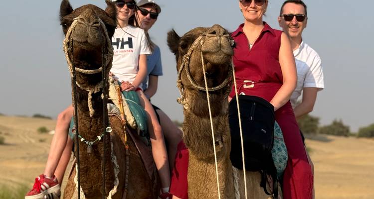 Dos parejas montando camellos juntas en un entorno desértico.