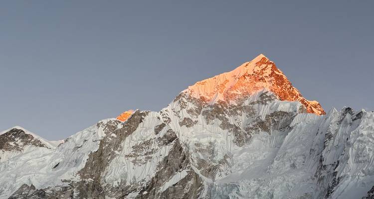 Pico montañoso nevado iluminado por el sol.