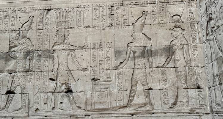 Sculptures anciennes sur un mur de pierre représentant des dieux égyptiens.