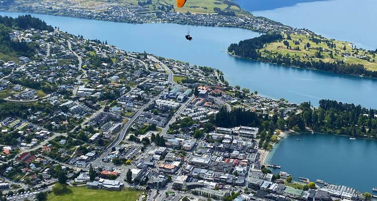 Vue aérienne d'une ville au bord d'un lac avec un parapentiste.