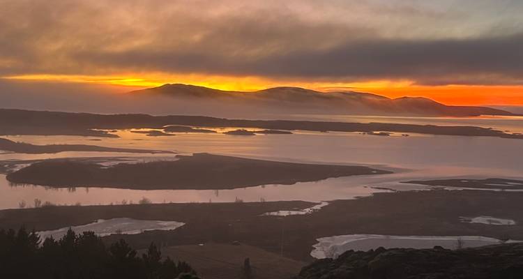 Coucher de soleil sur une étendue d'eau parsemée d'îles avec des nuages spectaculaires.
