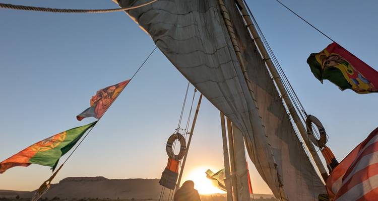Voilier sur l'eau pendant le coucher de soleil avec des drapeaux.