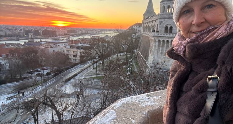 Una mujer tomándose una selfie con una vista del atardecer sobre una ciudad.