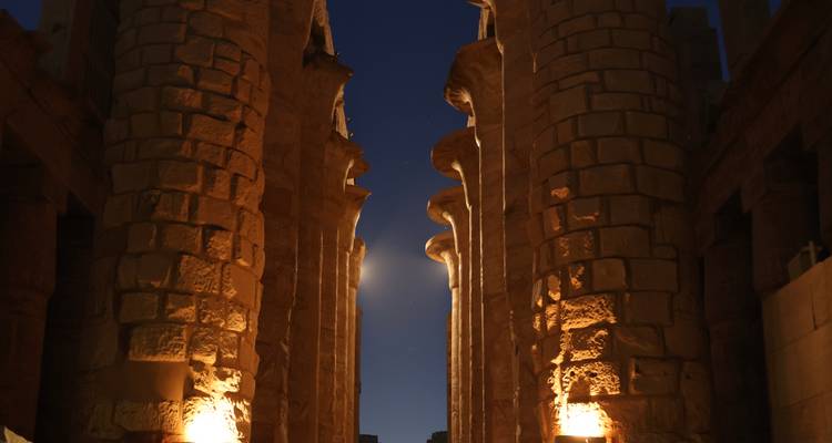 Colonnes de temple antique illuminées avec ciel nocturne.