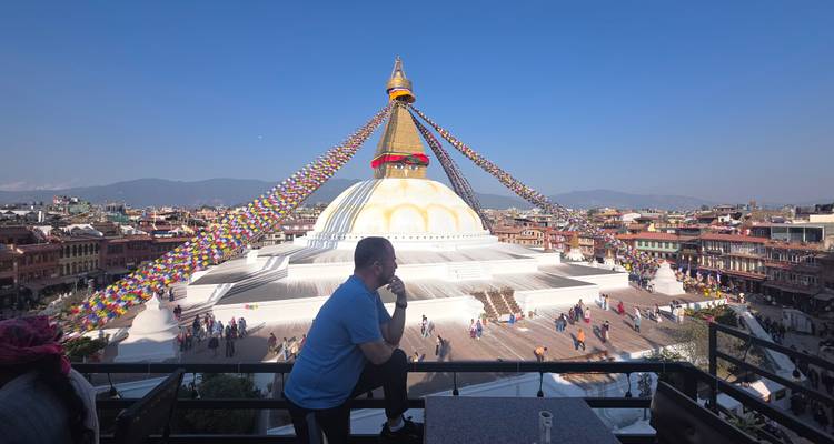 Une personne est assise sur un balcon avec vue sur le stupa de Boudhanath.