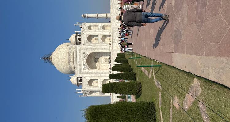 Touristen, die im Sonnenlicht auf das Taj Mahal zugehen.