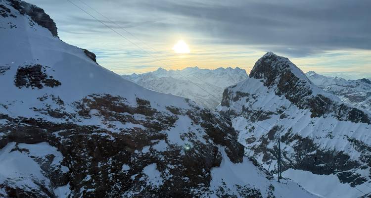 Paisaje montañoso nevado al atardecer con un cielo despejado.