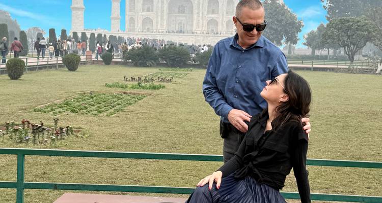 Pareja sentada junta con el Taj Mahal de fondo.