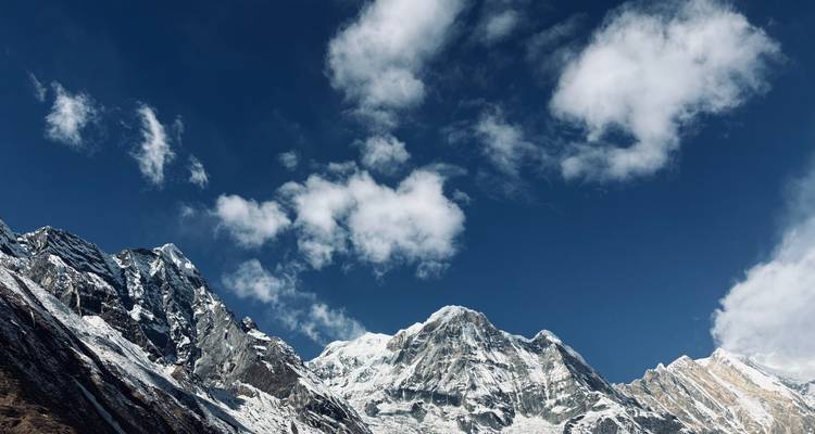 Montañas cubiertas de nieve contra un cielo azul con nubes.