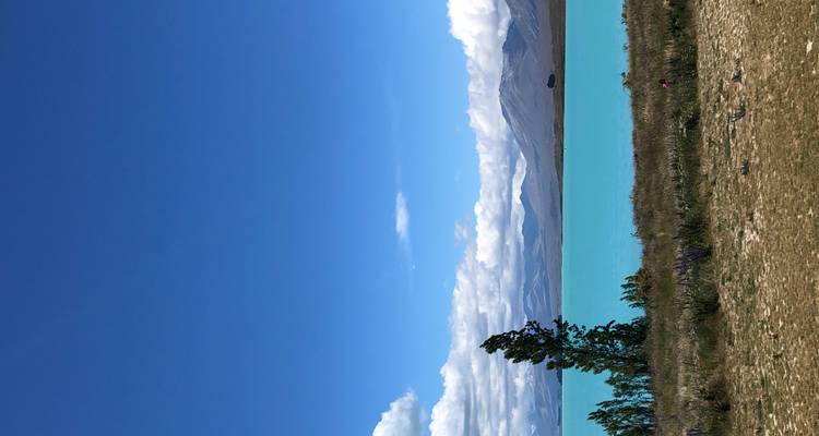 Türkiser See mit fernen Bergen unter einem strahlend blauen Himmel.