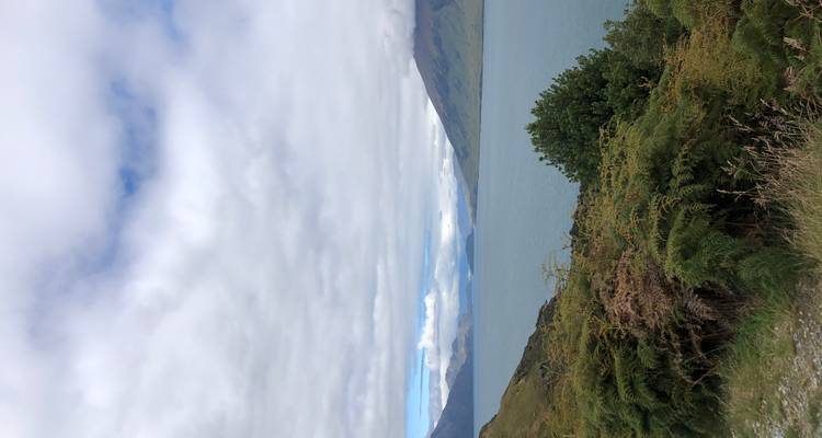 Con vista a un gran lago con colinas y un cielo nublado.