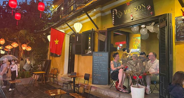 People sitting at a small bistro with Vietnamese decor in the evening.