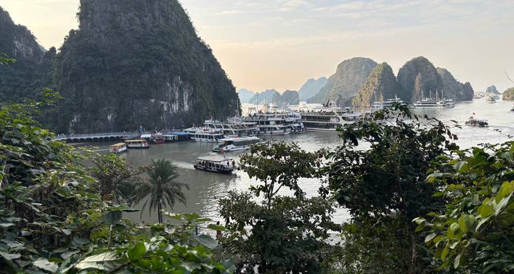 View of ships and boats in a bay surrounded by limestone cliffs.