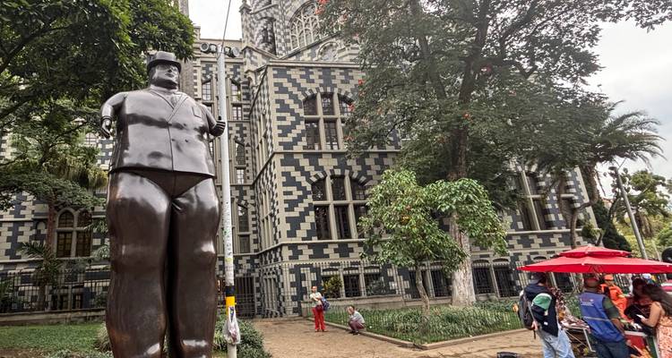 Sculpture de Botero devant un bâtiment historique à damier.