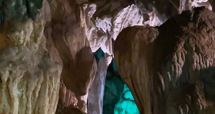 Interior de una cueva con estalactitas e iluminación colorida.