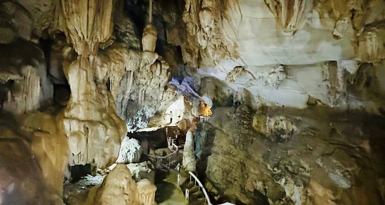 Interior de cueva grande con estalactitas e iluminación del sendero.