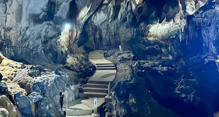 Sendero a través de una cueva con estalactitas e iluminación ambiental.