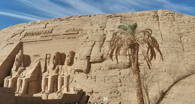 Façade de temple taillé dans la roche avec des statues dans le désert.