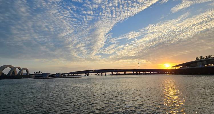 Atardecer sobre un río con un puente y nubes dramáticas.