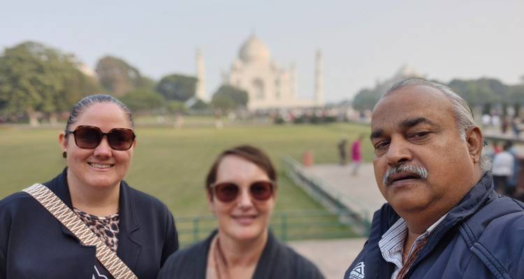 Three people posing with the Taj Mahal in the background.
