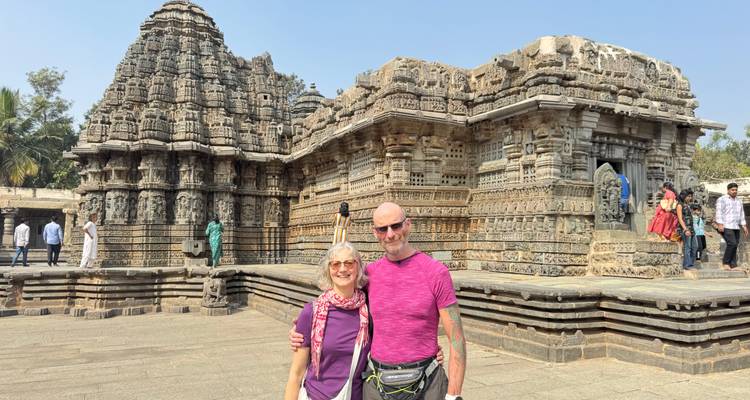 Un couple posant devant un temple antique aux sculptures complexes.
