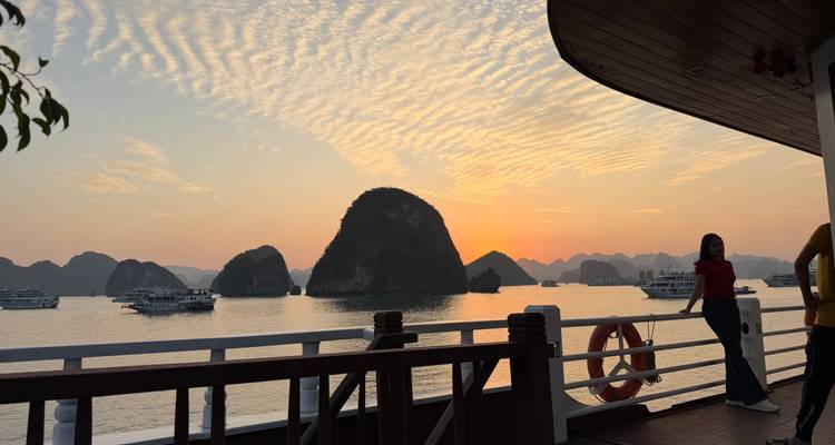 Mujer en un barco disfrutando de la vista del atardecer de karsts calizos.