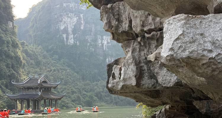 Gente en botes en un río, acantilados de piedra caliza al fondo.